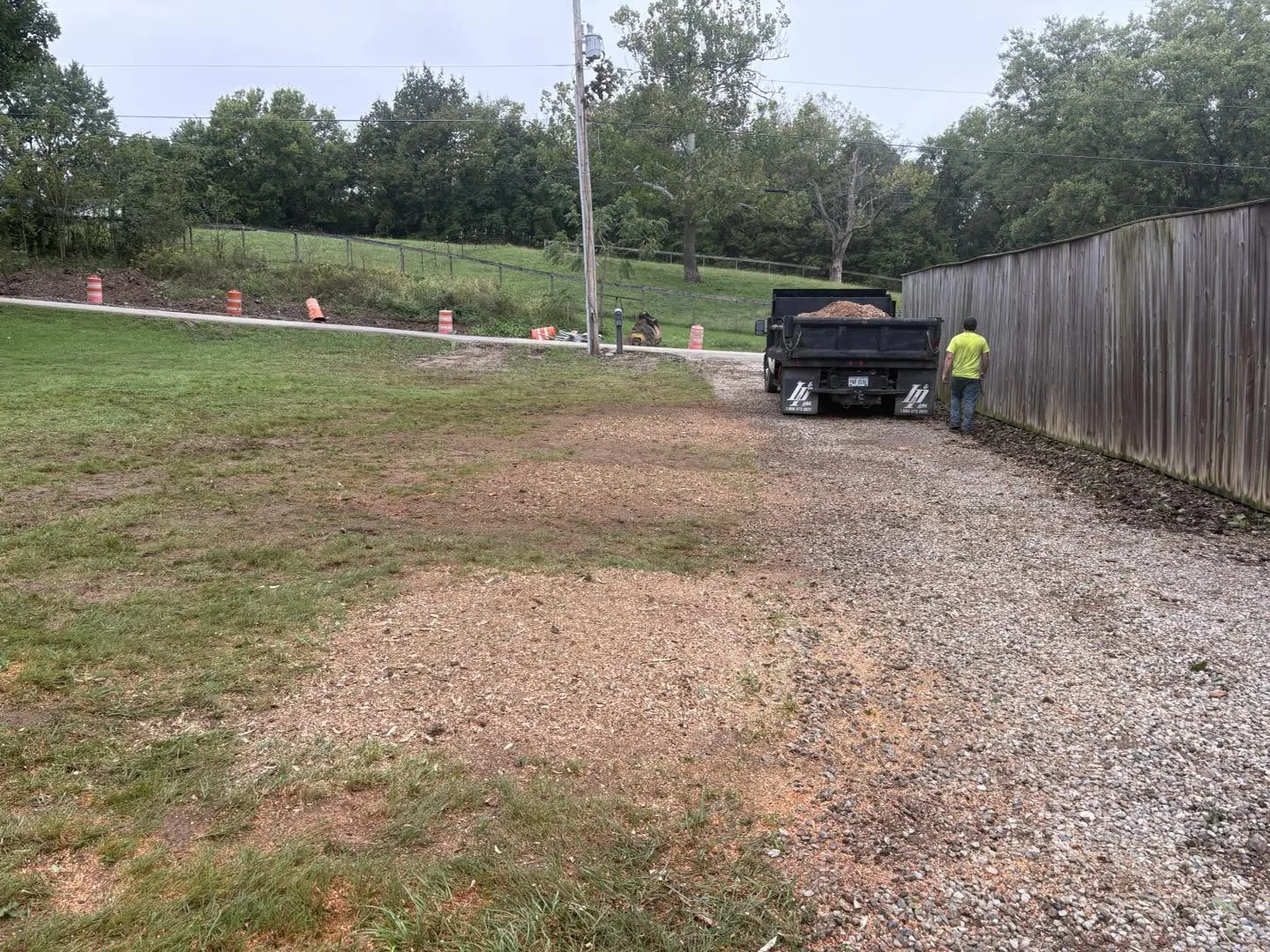 Gravel driveway and adjacent lawn after stump grinding, with the visible stumps removed